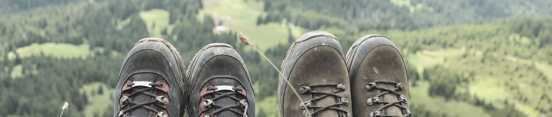 Two pairs of hiking boots with view of forested valley beyond